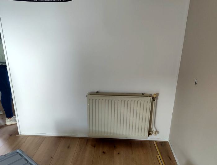 De muur met radiator voordat het dressoir er stond